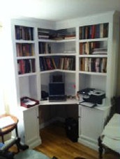 The image shows a white Billy bookcase with several shelves filled with books, and a desk with a chair and printer in the center.