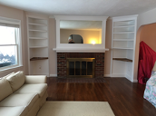 image shows a living room with custom built-in bookshelves and a fireplace, likely created by Old Bedford Fine Custom Carpentry