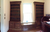 The image shows two dark wood bookcases on either side of a window.